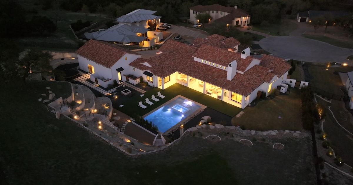 Estate lit at night from above, pool glowing